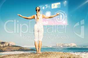 Composite image of blonde woman standing on beach on rock with a