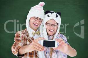 Composite image of geeky hipster couple taking selfie with smart