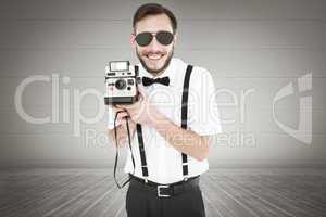 Composite image of geeky hipster holding a retro camera