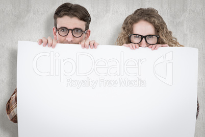 Composite image of geeky hipster couple holding poster
