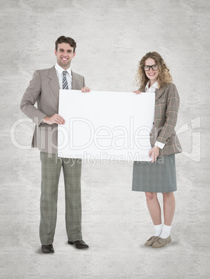 Composite image of hipster couple holding poster smiling at came