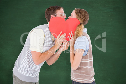 Composite image of geeky hipster couple kissing behind heart car