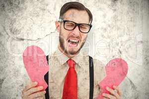 Composite image of geeky hipster crying and holding broken heart