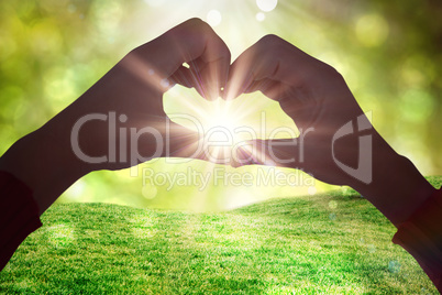 Composite image of woman making heart shape with hands