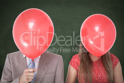 Composite image of geeky couple holding balloons in front of the
