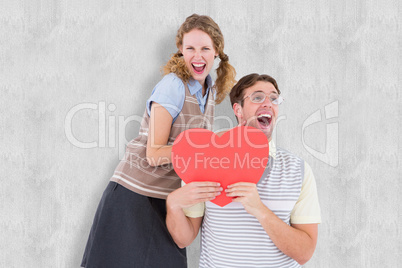 Composite image of excited geeky hipster couple with heart card