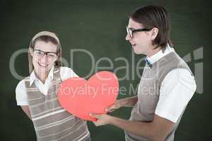 Composite image of geeky hipster offering red heart to his girlf