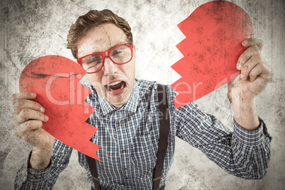 Composite image of geeky hipster holding a broken heart