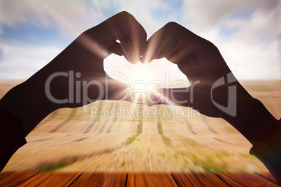 Composite image of woman making heart shape with hands