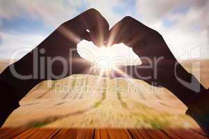 Composite image of woman making heart shape with hands