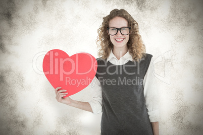 Composite image of geeky hipster holding heart card