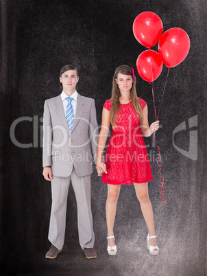 Composite image of unsmiling geeky couple standing hand in hand