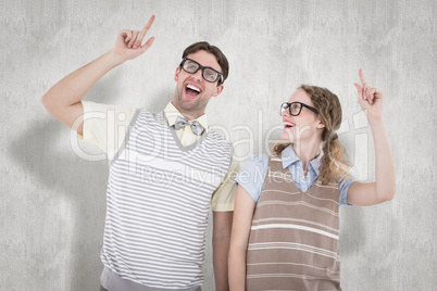 Composite image of happy geeky hipster couple pointing up