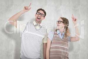 Composite image of happy geeky hipster couple pointing up