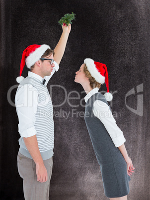 Composite image of geeky hipster kissing under mistletoe