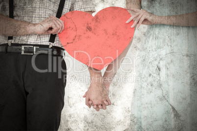 Composite image of hipster couple holding heart card
