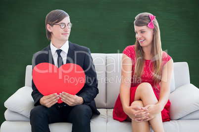 Composite image of cute geeky couple with red heart shape