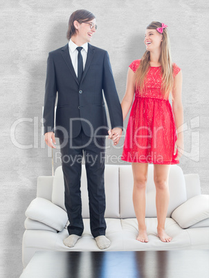 Composite image of geeky couple standing hand in hand on the cou