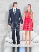 Composite image of geeky couple standing hand in hand on the cou