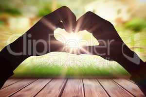 Composite image of woman making heart shape with hands