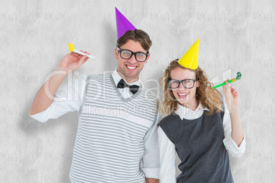 Composite image of geeky couple with party hat and party horn