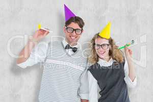 Composite image of geeky couple with party hat and party horn