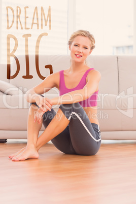 Composite image of athletic blonde sitting on floor smiling at c