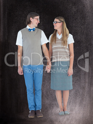 Composite image of geeky hipster couple holding hands and lookin