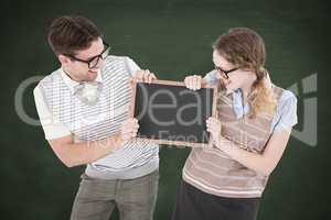 Composite image of geeky hipster couple holding little blackboar