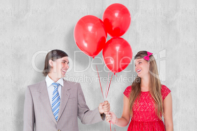 Composite image of smiling geeky couple holding red balloons