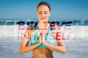 Composite image of fit woman meditating on the beach