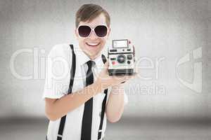 Composite image of geeky hipster holding a retro camera