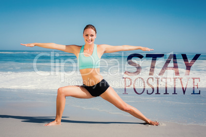 Composite image of fit woman standing on the beach in warrior po