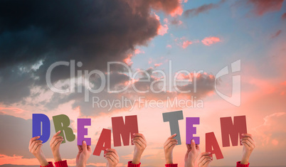 Composite image of hands holding up dream team