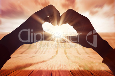 Composite image of woman making heart shape with hands