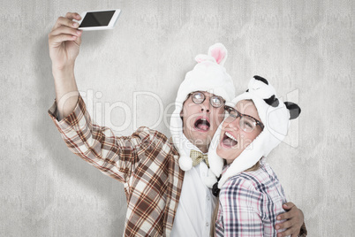 Composite image of geeky hipster couple taking selfie with smart