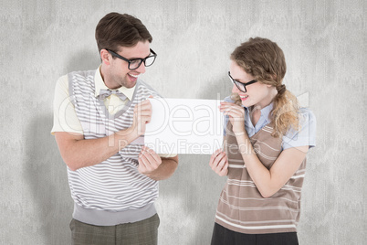 Composite image of geeky hipster couple holding poster