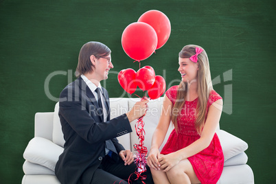 Composite image of cute geeky couple with red balloons