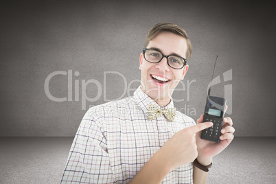 Composite image of geeky hipster holding a retro cellphone