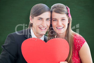 Composite image of cute geeky couple smiling and holding heart