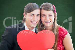 Composite image of cute geeky couple smiling and holding heart