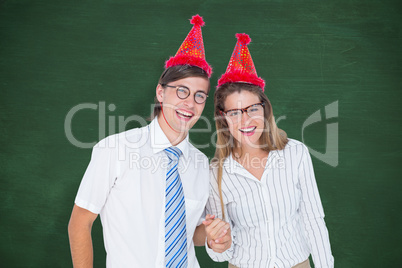 Composite image of happy geeky hipster couple with party hat