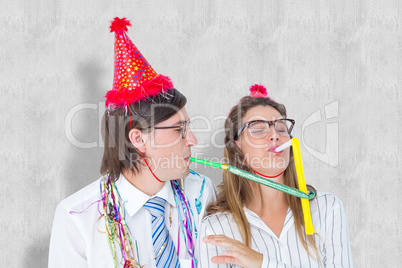 Composite image of geeky hipster wearing a party hat with blowin