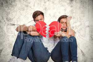 Composite image of young couple holding broken heart