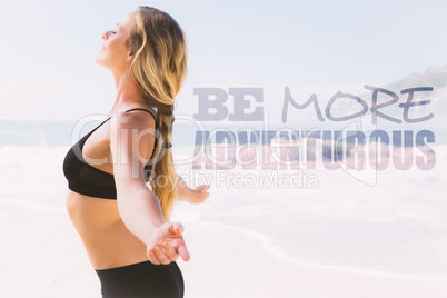 Composite image of fit blonde standing on the beach with arms ou