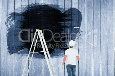 Composite image of man with paint roller standing by ladder