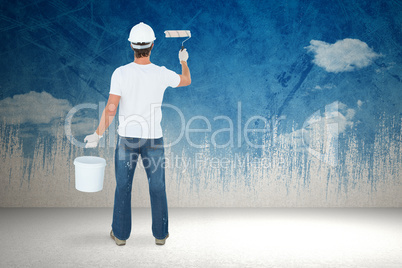 Composite image of rear view of man using paint roller