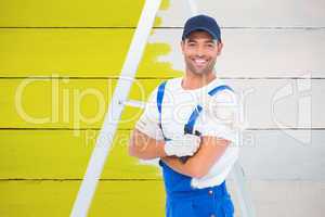 Composite image of smiling handyman with paint roller standing b