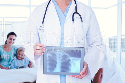 Composite image of doctor looking at xray on tablet