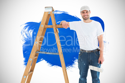 Composite image of happy man with paint roller standing by ladde